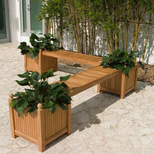 70530 double teak planter bench set with three green plants in planters on concrete patio with shrubs and sliding glass doors in background