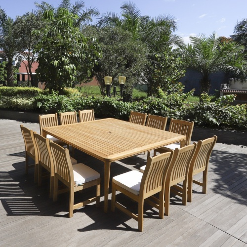 70879 Veranda 13 piece teak Square Dining Set with optional seat cushions angled view on deck with trees shrubs and buildings in background