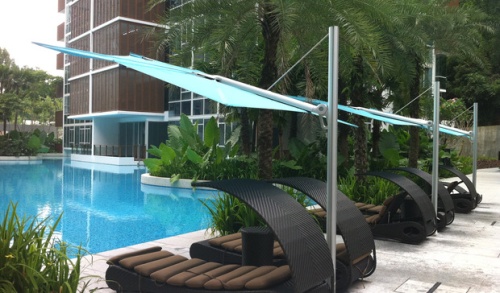 sp2590set spectra solo umbrella and paver base showing angled side view of three over lounge chairs on pool deck facing pool and landscaping trees and hotel in background