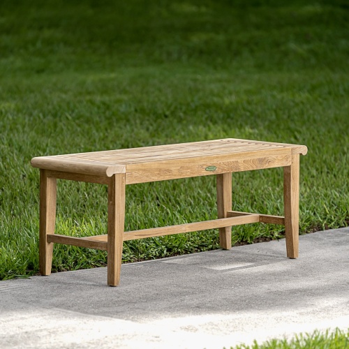 13915 Laguna 4 foot long teak Backless Bench on concrete walkway with grass in background