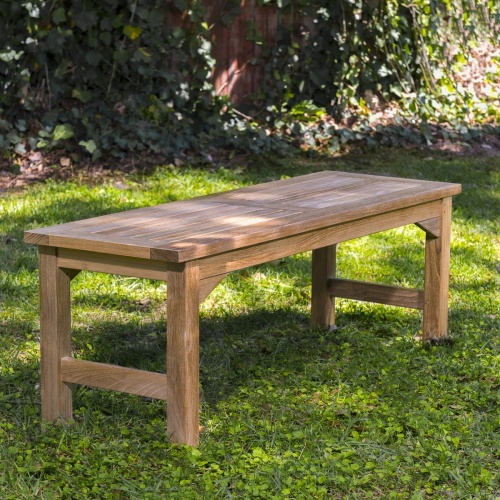 13940 Veranda 4 foot Teak Backless Bench side angled view on grass area with trees & shrubs in background