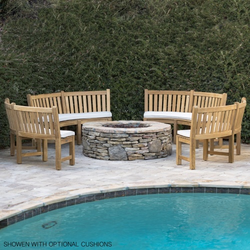 70657 Buckingham Bench Set showing 4 curved benches in a circle with optional canvas color cushions on stone concrete patio around a fire pit with pool in front and bushes in background