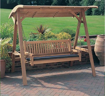13955 veranda teak swinging bench and canopy set on brick patio with shrubs and grass in background
