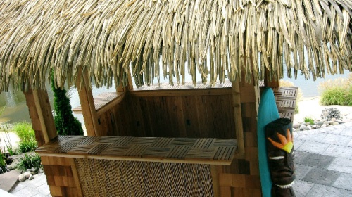 70400 parquet teak tiles on tiki bar counter on stone patio landscape plants and water in background