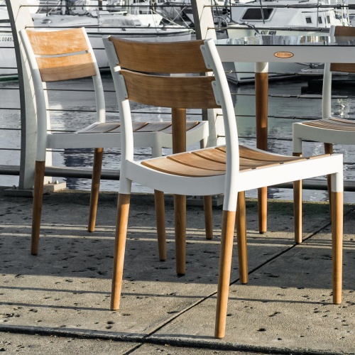 70751 Bloom teak and white powder coated aluminum Dining Side Chair angled on concrete dock overlooking marina