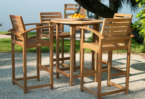 12466 Somerset 5 piece Teak Bar Table Set with bowl oranges on concrete patio with grass and trees in background overlooking ocean