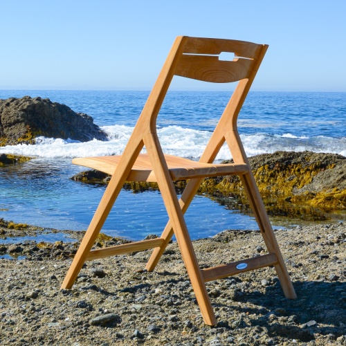 11916 Surf teak folding side chair left side view on beach facing ocean and blue sky
