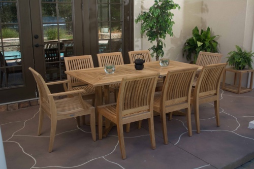 70295 Pyramid Laguna 9 piece Rectangular Dining Set on stone patio with 2 glass holders with votives and black teapot on table and french doors on left and 3 potted plants in background