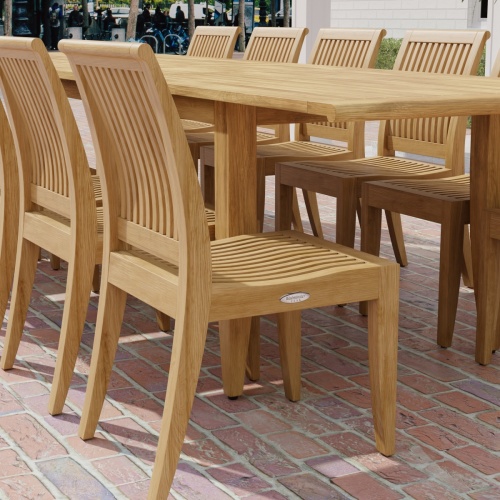 70810 Laguna 13 pc Teak Dining Set showing partial corner angled view of the dining table and 6 dining chairs on a brick paver patio.