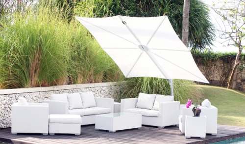 sp25100set spectra solo umbrella and paver base white canopy over white sofa set on wood deck stone railing behind deck tall grass shrubs and grass in background