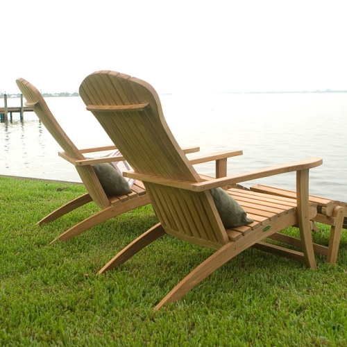 70000 two Adirondack Chair with footrest and cushions rear side view on green grass in facing lake with dock and land on side background