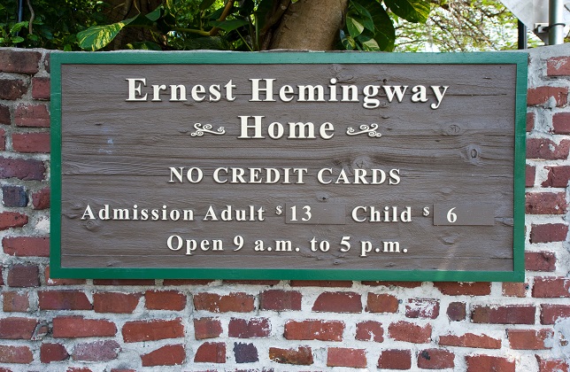 Wooden sign on a brick wall outside the entrance of Hemingway’s house in Key West, Florida.