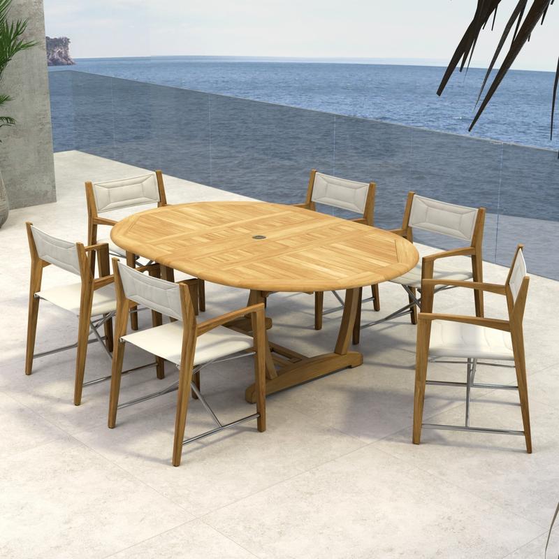 alt="70366 Oval Odyssey Chair 7 pc Dining Set of Martinique Oval Table and 6 Odyssey Director Chairs on outdoor terrace with potted tree and ocean background"