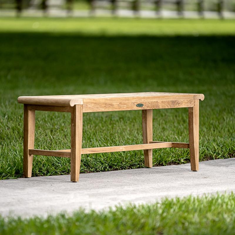 alt="13915 Laguna 4 foot long teak Backless Bench on concrete walkway with grass in background"