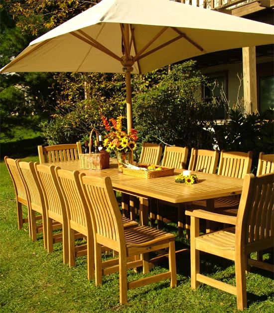 alt="12218 Veranda Chair With Arms with Veranda grand extension table with optional rectangular umbrella in table on grass lawn and landscape plants in background"