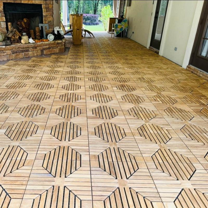 alt="18408P diamond teak tiles assembled together on an outdoor patio with a stone fireplace and trees in background "