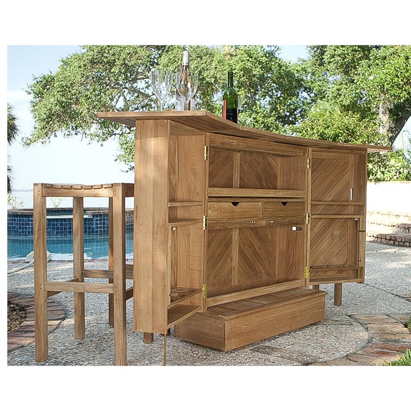 alt="70084 somerset teak five piece bar set fully opened showing two wine glasses and two wine bottles on stone patio facing pool with oak tree and palms in background"