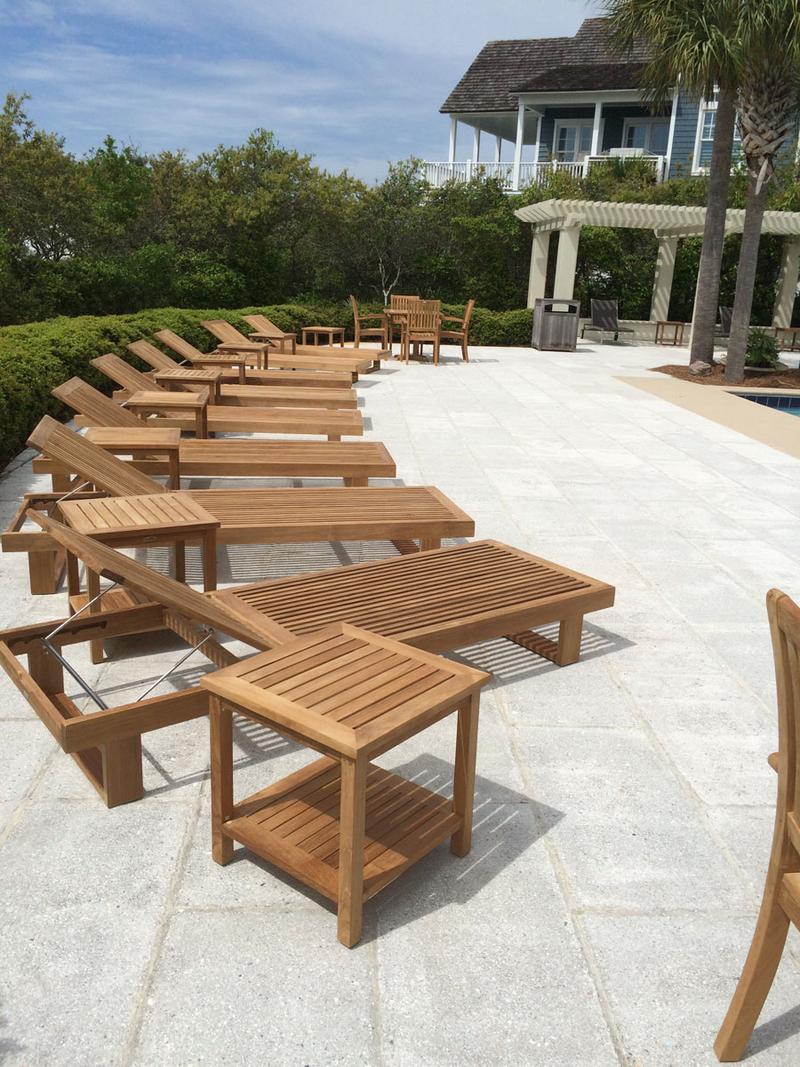 alt="16770DP Horizon teak Chaise Lounger showing eight  with side tables on pool deck with palm trees house and vegetation in background"