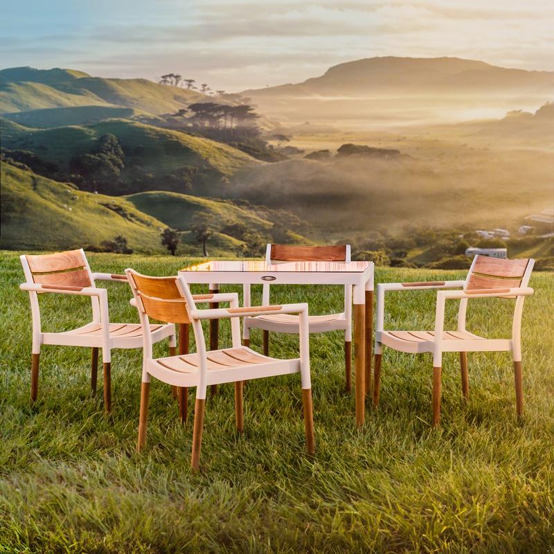 alt="70448 Bloom 5 piece Dining Set of a 32 inch square teak and powder coated aluminum dining table and 4 dining armchairs on grass pasture with mountains in background"