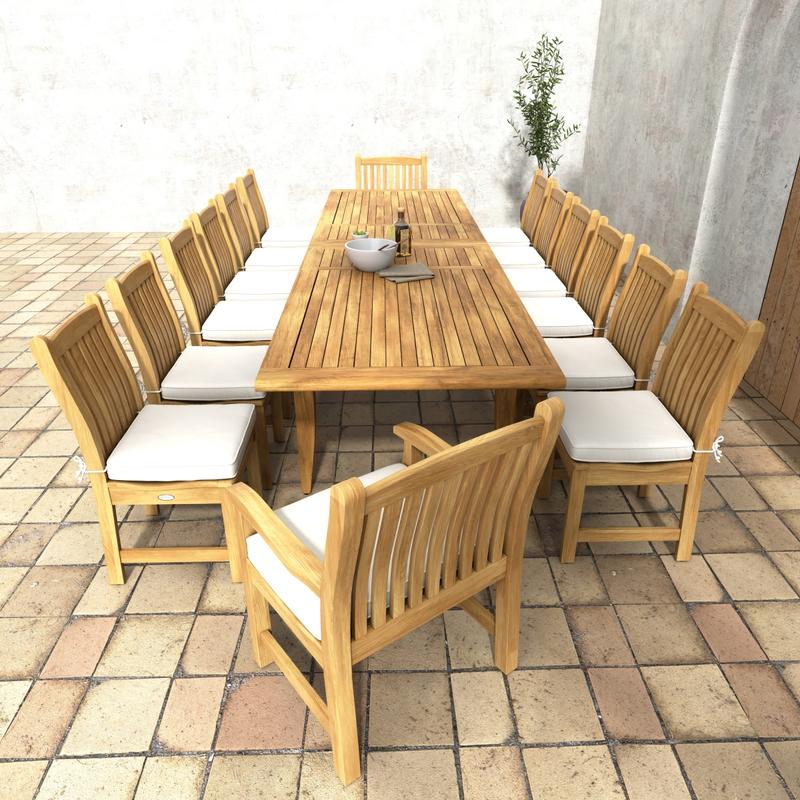 alt="70361 Grand Laguna 15 piece teak Dining Set of 12 teak dining chairs with optonal cushions around a teak rectangular extendable dining table angled end view on patio and a potted tree in background "