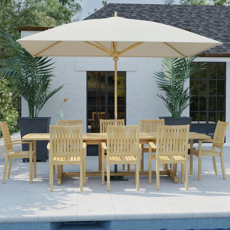 alt="70759 Sussex Veranda 9 pc Teak Patio Dining Set with optional umbrella in angled side view on pool deck with house and windows and 2 potted plants in background "