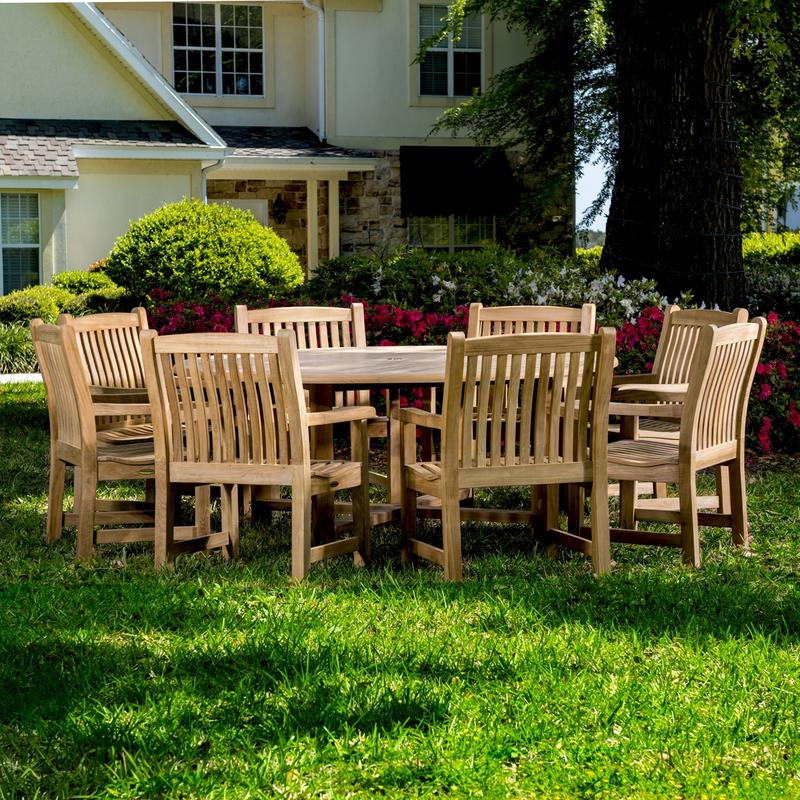 alt="70173 Buckingham 9 pc teak Dining Set of 8 dining armchairs and 6 foot round dining table on grass field with flowers trees and house in background"