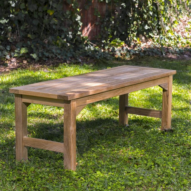alt="13940 Veranda 4 foot Teak Backless Bench side angled view on grass area with trees & shrubs in background"