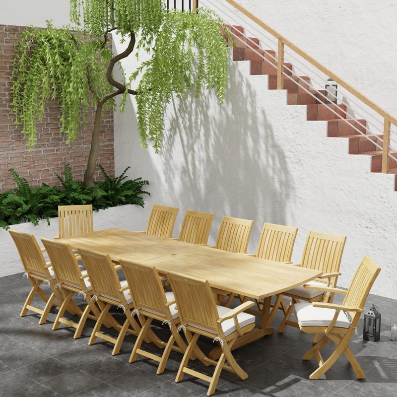alt="70095 Barbuda Teak 13 pc Patio Set of a 10 foot rectangular extension table and 12 folding reclining armchairs in end angled with plants next to a staircase in background"