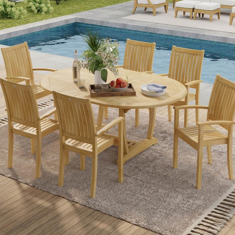 alt="70214 Martinique Sussex Teak 7 pc Dining Set of Martinique Teak Oval Table and 6 Sussex Teak stacking Arm Chairs aerial view next to pool with plants in background"