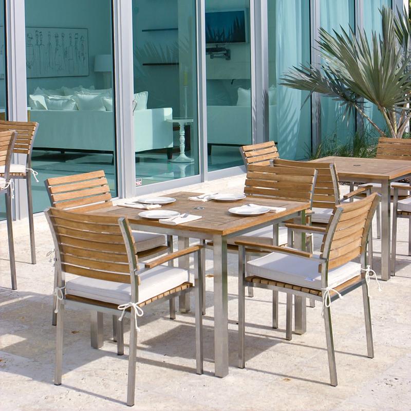 alt=" 70014 Vogue teak and stainless steel 5 piece Dining Set of 4 chairs with optional seat cushions and 36 inch square table with 4 place settings on outdoor patio plant and glass doors in back"