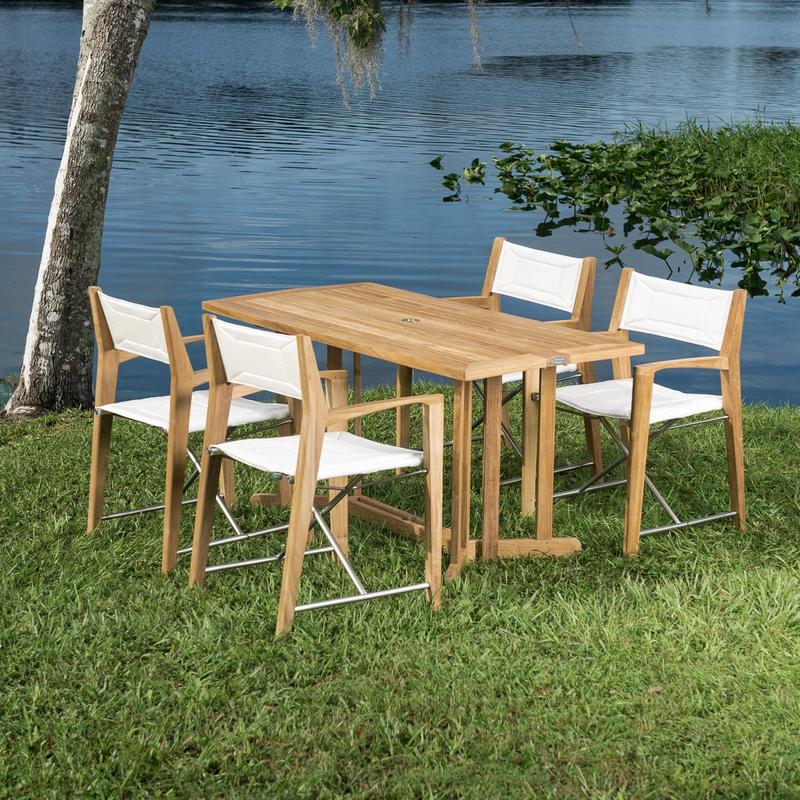 alt="70476 Odyssey 5 piece Outdoor Dining Set of 4 folding director chairs and 5 foot rectangular teak dining table on grass field overlooking a blue lake"
