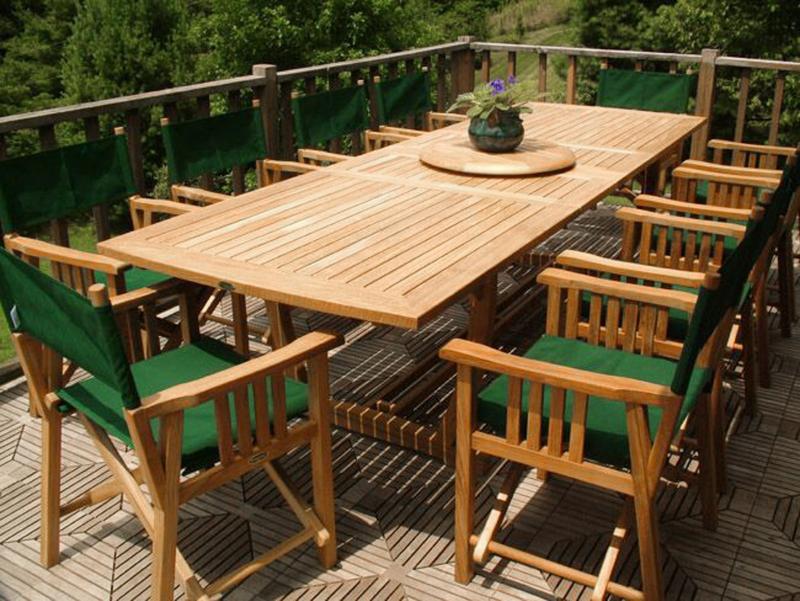alt="70006 Veranda teak 11 piece director chair dining set potted violet plant on teak lazy susan on teak floor deck with trees in background"