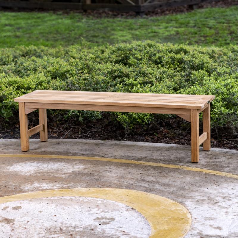 alt="13929 Veranda teak 5 foot long Backless Bench angled side view on stone patio with bushes in background"