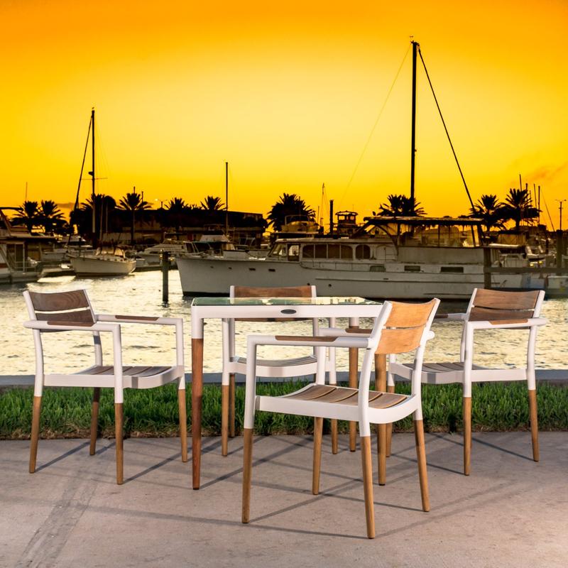 alt="22916 Bloom Dining chair of 4 chairs around Bloom Square glass top table on concrete patio overlooking boat dock with sunset in background"