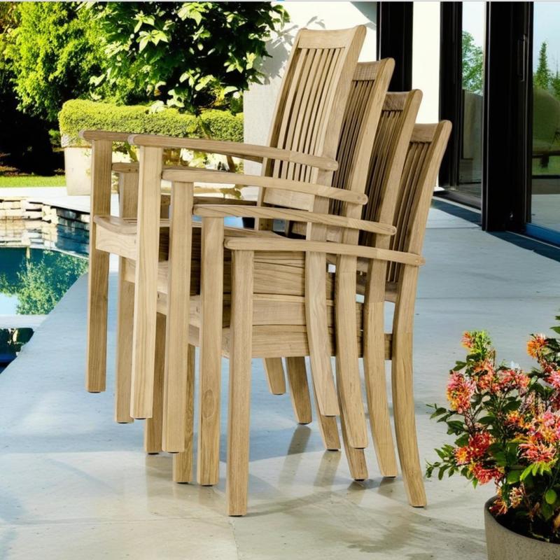 alt="12196ST Sussex Dining Chair showing 4 stacked high angled side view on pool deck next to pool with plant edge and house glass slider in background  "