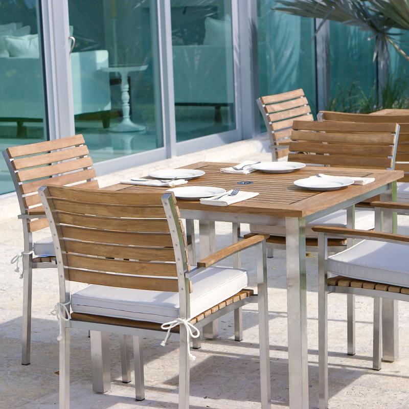 alt="70014 Vogue teak and stainless steel 5 piece Dining Set closeup view with 4 place settings and glass sliding doors in background"