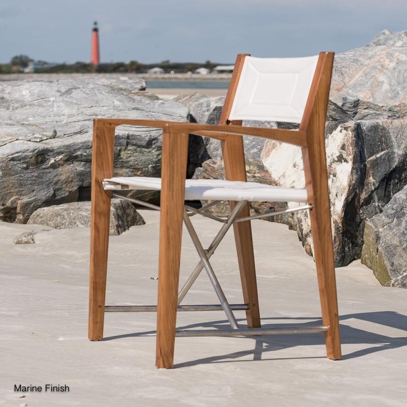 alt="12915F Odyssey Teak and 316L Stainless Steel Chair facing left view on sandy beach by boulders"