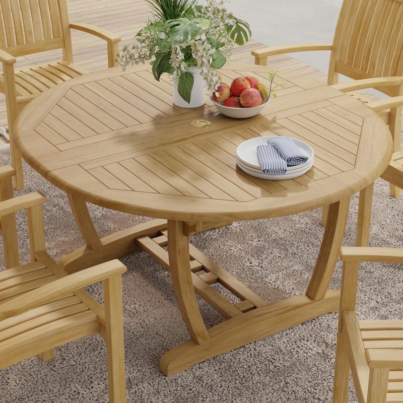 alt="15548 Martinique Teak Extension Table in angled top view collapsed position on patio with plate and flower vase on table and 4 chairs in background"