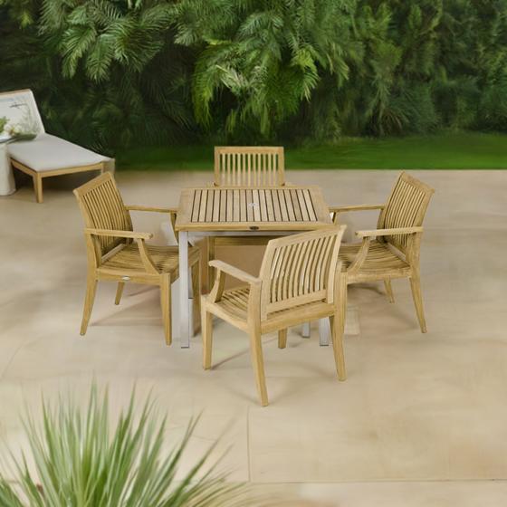 70603 Vogue Laguna 5 pc Dining Set of Vogue Teak 36 inch Square Table and 4 Laguna Dining Arm Chairs angled aerial view on patio with plants and white chaise in the background 