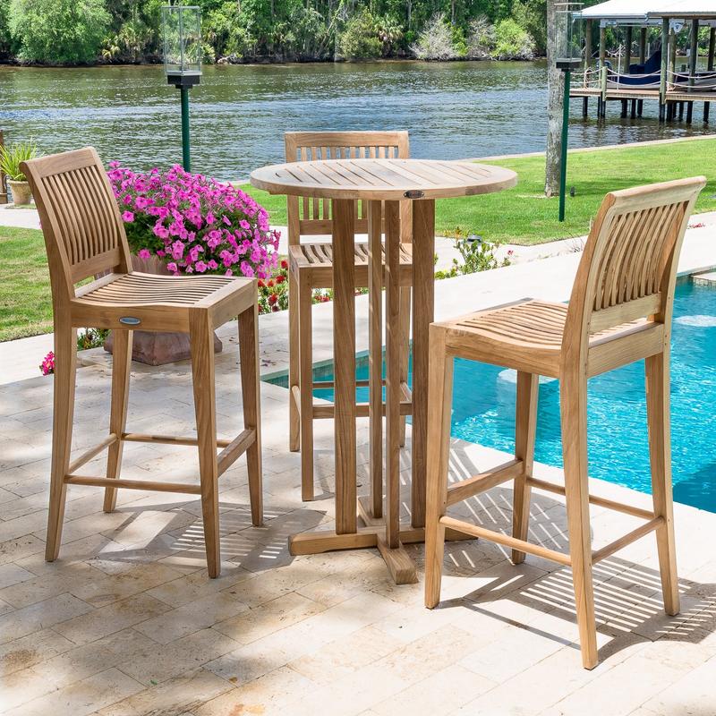 alt="70503 Laguna 4 piece Pub Set on paver patio next to pool with flowering plants grass lawn lamp post walk way lake and screened boathouse and trees in background"