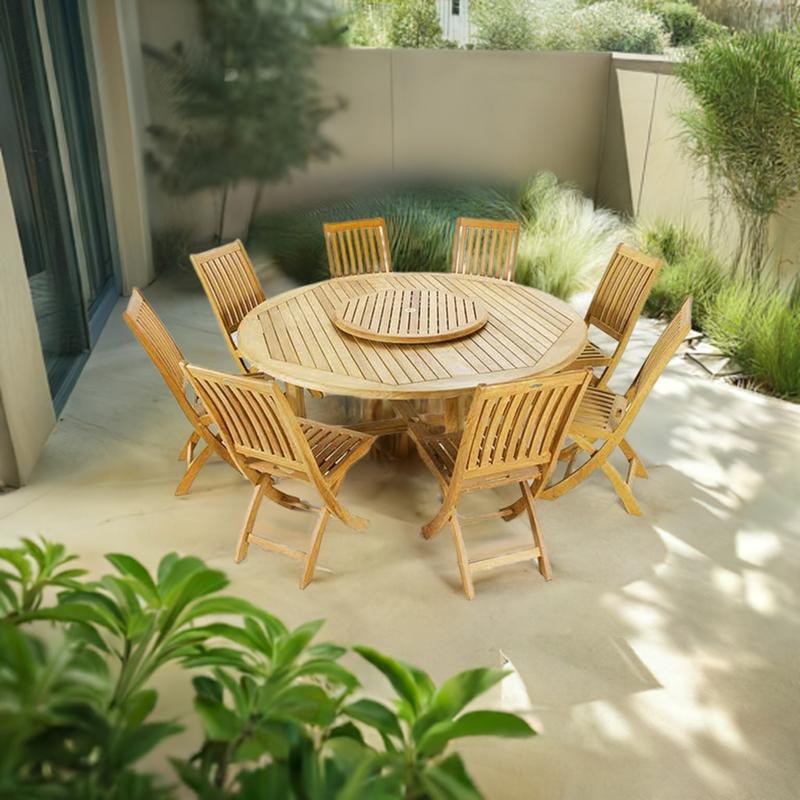 alt="70018 Buckingham Barbuda 9 pc Dining Set angled with optional Lazy Susan in the center on a stone patio surrounded by plants next to glass doors and a privacy wall and trees in the background "