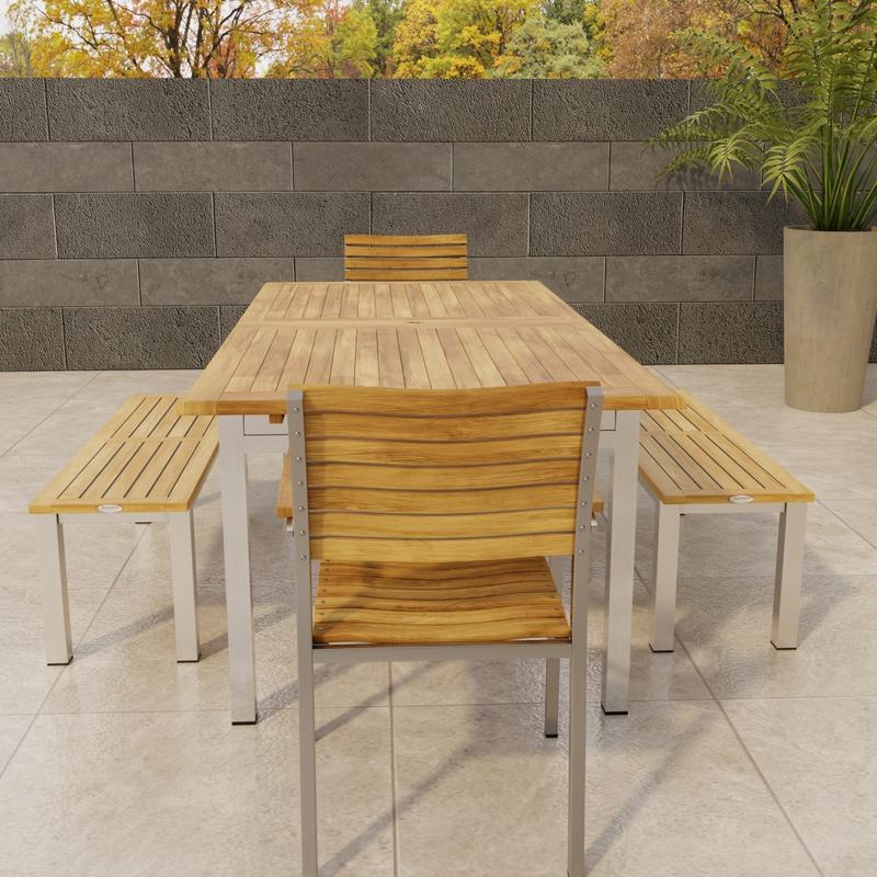 alt="70445 Vogue Bench Dining Set end view of Stainless Steel and Teak Extension Table and 2 Dining Chairs and two 4 ft Backless Benches  on tile patio with fence and trees in background"