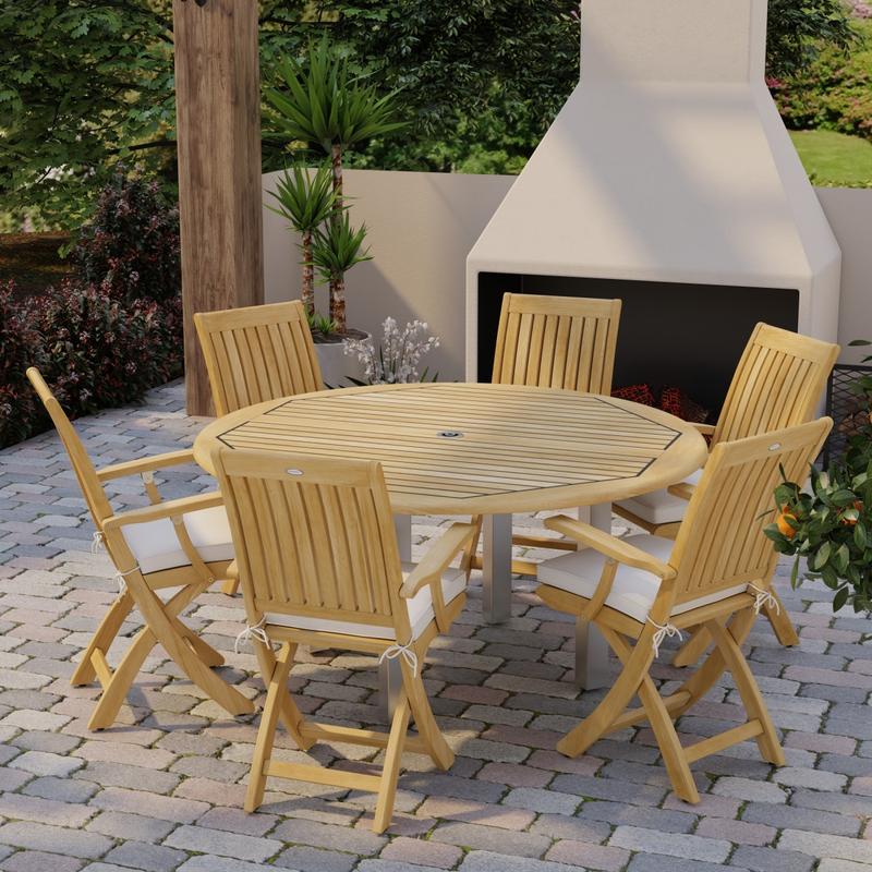 alt="70357 Vogue Barbuda 7 pc Dining Set angled side view on brick paver patio in front of an outdoor fireplace and landscape plants in background"