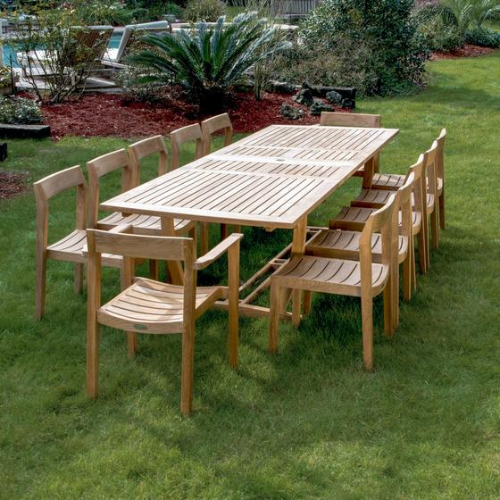 70800 Grand Horizon 13 piece teak Dining Set angled end view on grass lawn with pool and vegetation in background