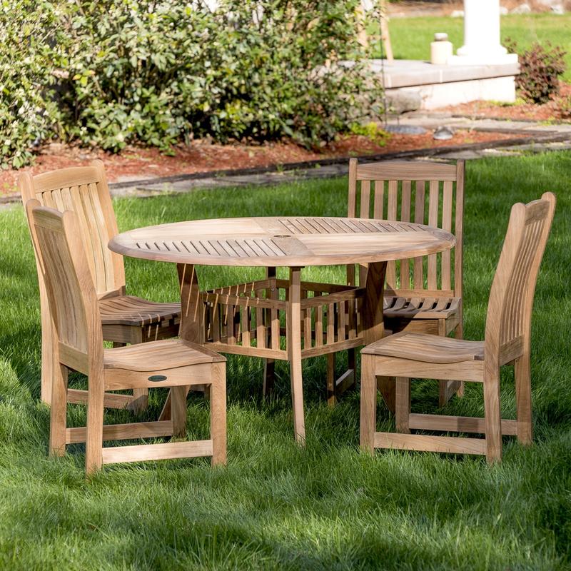 alt="70040 Veranda Hyatt 5 piece teak Dining Set of 4 side chairs and 48 inch round dining table on grass lawn with concrete walkway and mulched landscaped area in background "