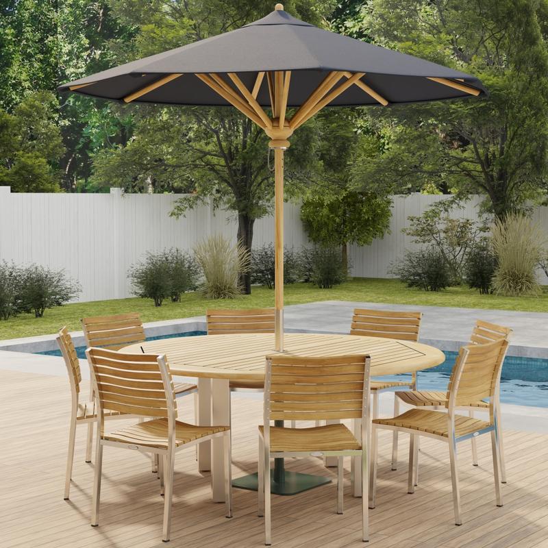alt="70444 Vogue Teak Dining Set for 8 with optional umbrella side angled view on outdoor deck  next to a pool with fence and plants and trees in background "