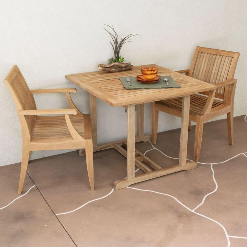 alt="70654 Laguna Square 3 piece teak Dinette Set showing plant and 2 plates and 2 bowls a fork and spoon set on stone patio against a wall "