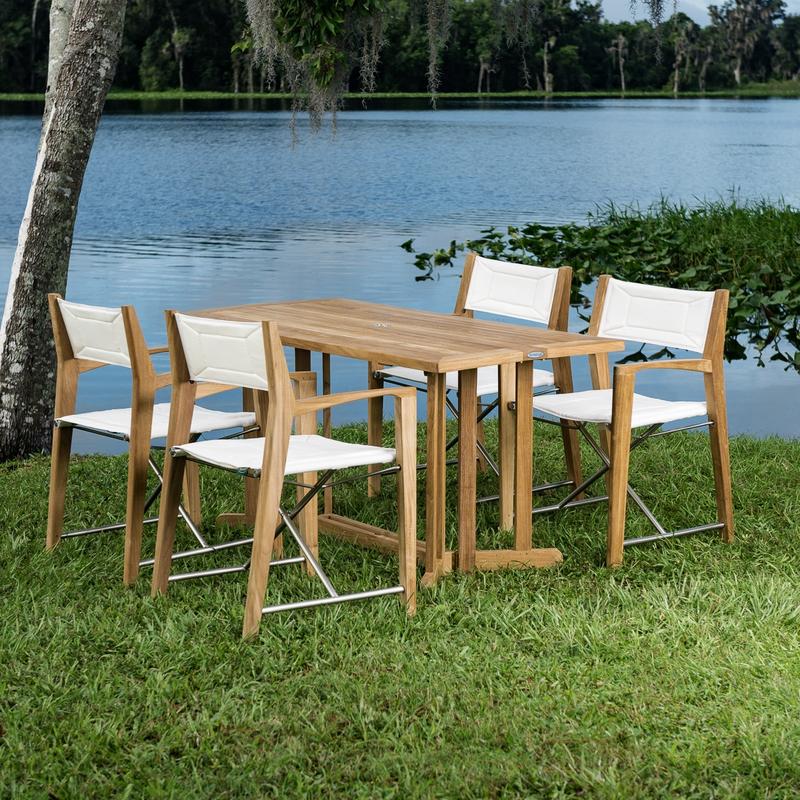 alt="70476 Odyssey 5 piece Outdoor Dining Set of 4 folding director chairs and 5 foot rectangular teak dining table on grass field overlooking a blue lake"