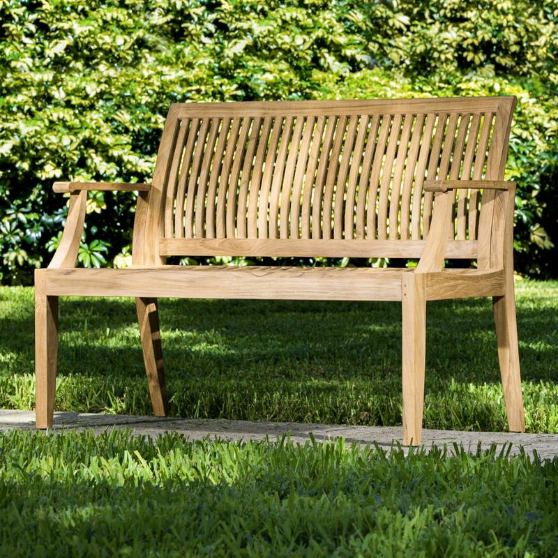 alt="13810 Laguna 4 foot Teak Bench front angled view on concrete walkway with bushes in background"
