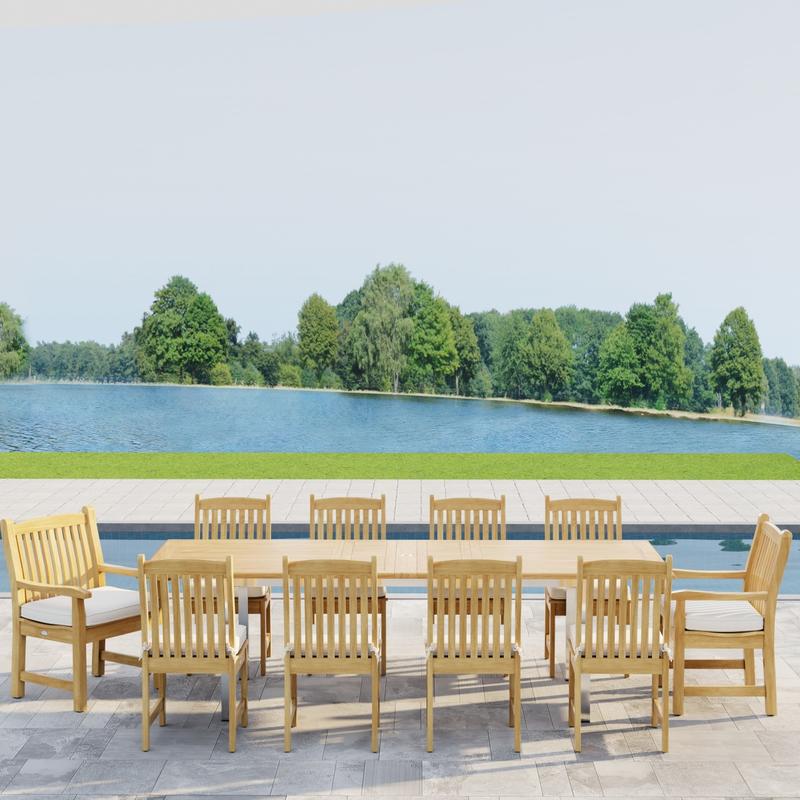 alt="70826  Vogue Veranda 13 pc Teak Dining Set with optional seat cushions showing side profile view on patio in front of a pool with a lake and trees in background"